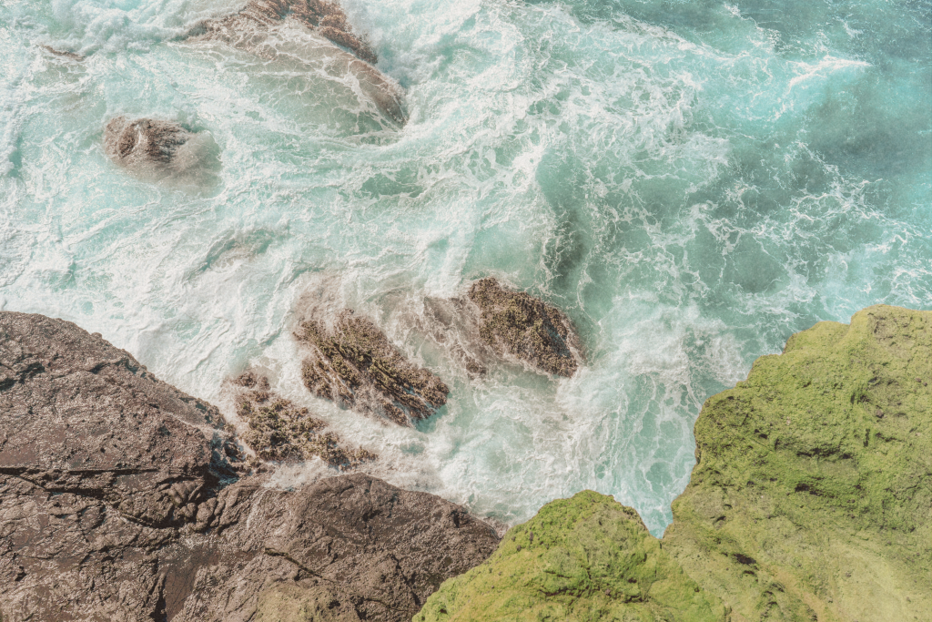 A foamy ocean view in Oahu with waves crashing against a rugged volcanic shoreline