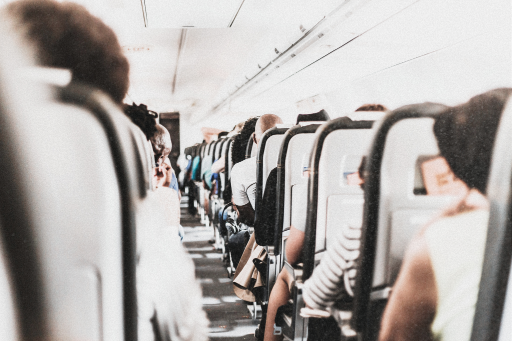 Passengers sitting inside an airplane, some reading, others resting, with soft lighting creating a calm in-flight atmosphere.
